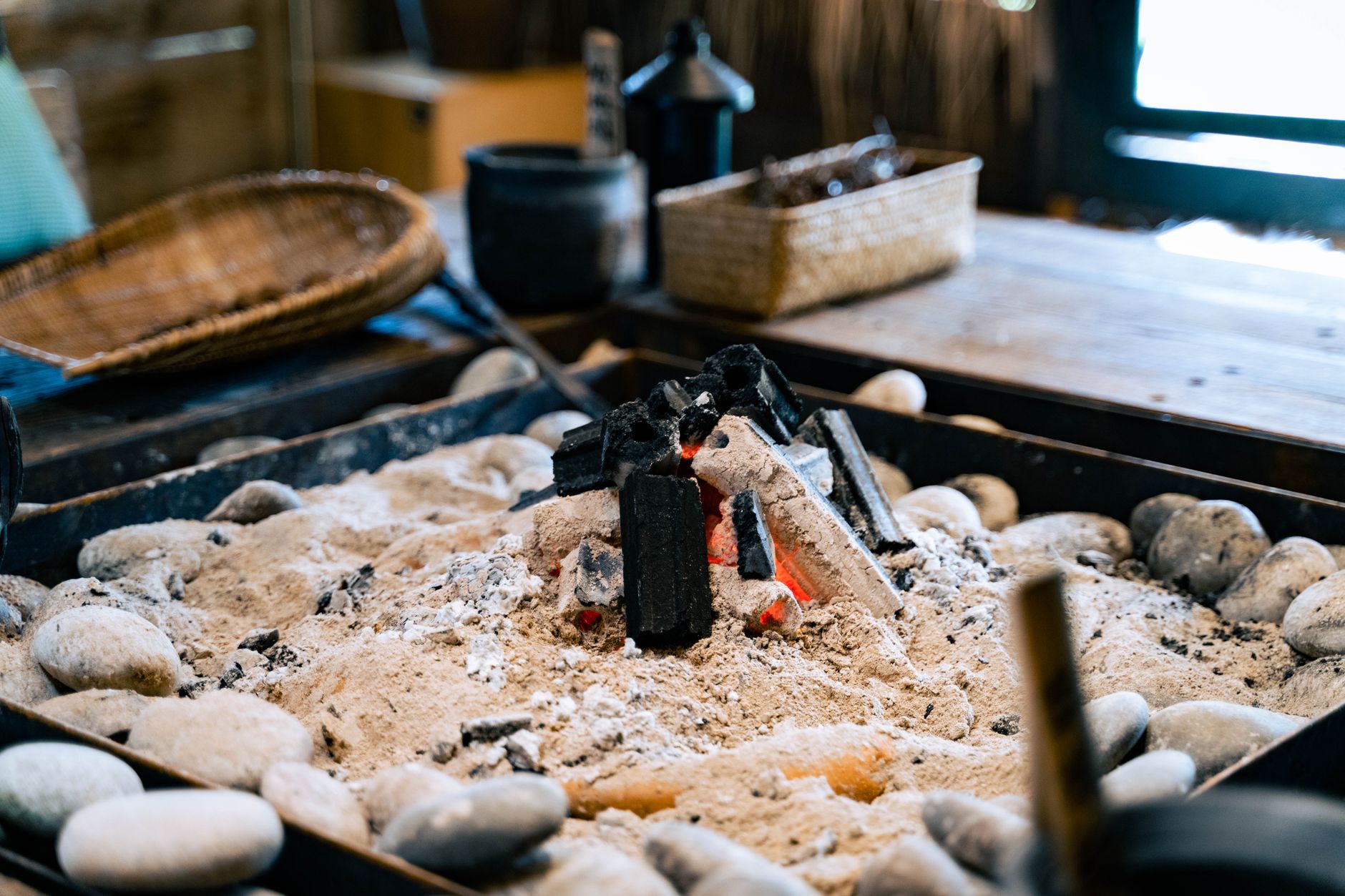 A close-up of a rustic indoor fireplace with burning coals in a sandpit, perfect for relaxation.